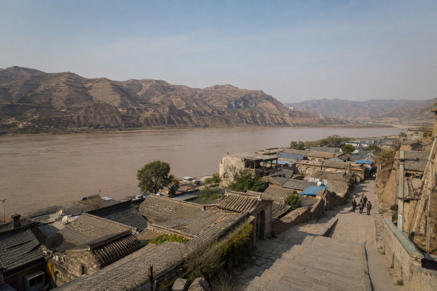 黄河东岸碛口古镇灰瓦商街与黄土山坡的旅行配图